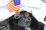 A boy waves the American flag as he waits for a visit by President Clinton.